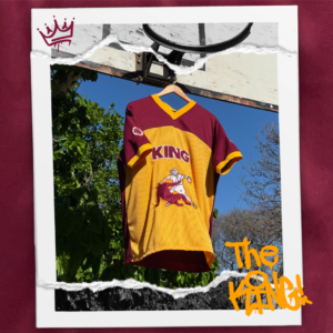 Jersey bordó combinado con amber, holgado y fresco confeccionado en polyester. Diseño exclusivo con múltiples bordados. Frente: Imagen de Jesús venciendo al diablo en una jugada de básquet + texto KING. Espalda: texto KING y el número 7. Manga derecha: escudo con pelota básquet y la frase “He is the King”. Manga izquierda: texto “You’ll never walk alone again“.