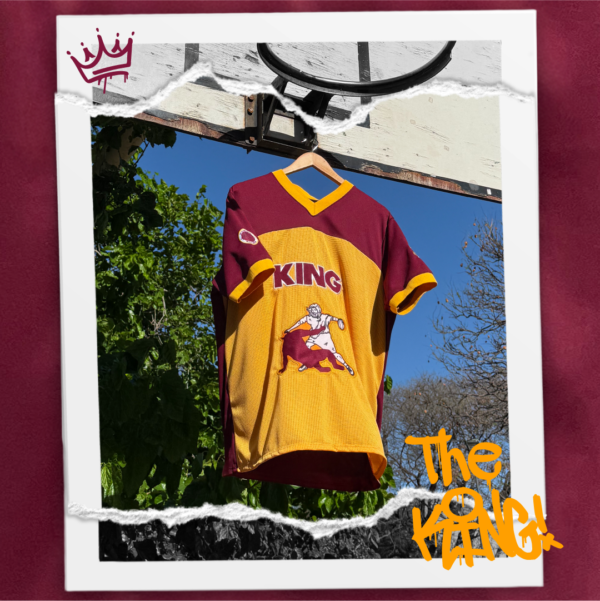 Jersey bordó combinado con amber, holgado y fresco confeccionado en polyester. Diseño exclusivo con múltiples bordados. Frente: Imagen de Jesús venciendo al diablo en una jugada de básquet + texto KING. Espalda: texto KING y el número 7. Manga derecha: escudo con pelota básquet y la frase “He is the King”. Manga izquierda: texto “You’ll never walk alone again“.