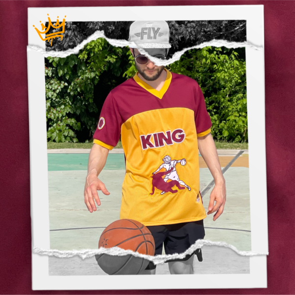 Jersey bordó combinado con amber, holgado y fresco confeccionado en polyester. Diseño exclusivo con múltiples bordados. Frente: Imagen de Jesús venciendo al diablo en una jugada de básquet + texto KING. Espalda: texto KING y el número 7. Manga derecha: escudo con pelota básquet y la frase “He is the King”. Manga izquierda: texto “You’ll never walk alone again“.